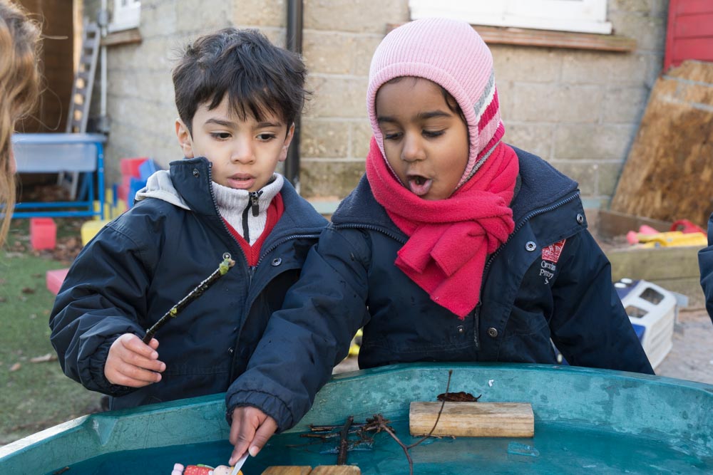 Two children playing in a wet tray